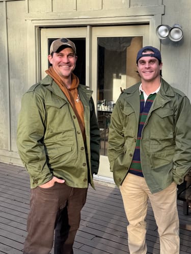 Two customers showing the fit of their US Army M-1943 Field Jackets layered over casual shirts.