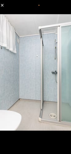 Anmelderens dusjområde før renovering, som viser de originale lyseblå veggplatene.