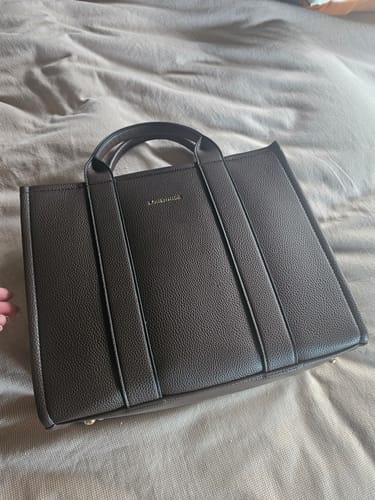 Customer's chocolate Manhattan Tote Bag lying on a bed, showing its structured form and pebbled vegan leather.