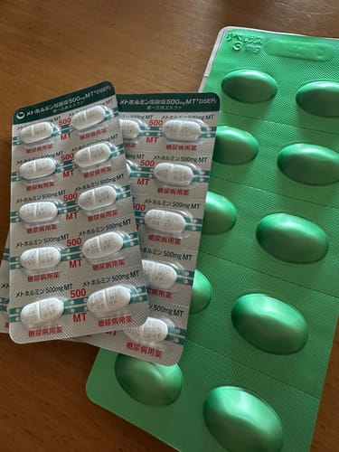 レビュアーのリベルサスとメトホルミンのブリスターパック。木製のテーブルの上に置かれている。