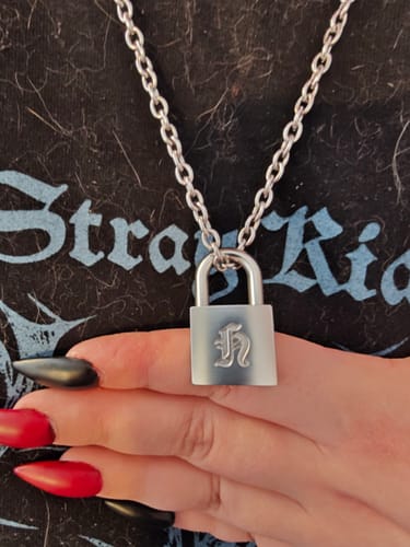 A customer wears the STRAY KIDS necklace, showing the silver-toned padlock pendant with an engraved 'H'.