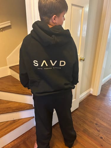 Customer photo showing the back of the black SAVD Oversized Hoodie being worn by a young person indoors.