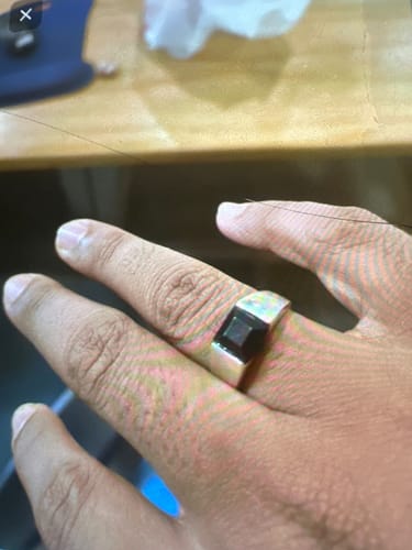 Close-up of a reviewer's hand wearing a wide silver-colored ring with a square black stone.