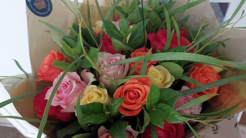 Close-up of a customer's Mixed Rose Bouquet with vibrant, colorful roses and greenery.