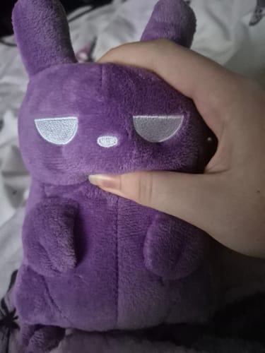 A customer's hand holds the purple Spearmaster Slugpup Plush, gently squishing its soft face.