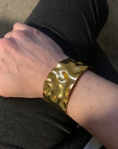 Customer wearing the wide, wavy 18K Gold Cuff Bracelet on their wrist.