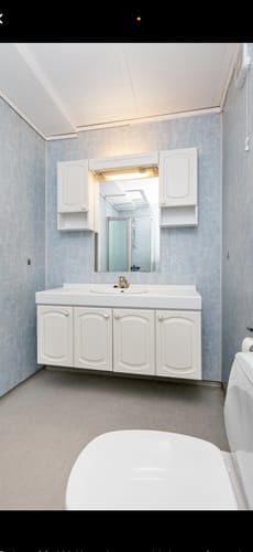 Anmelderens bad før renovering, med lyseblå veggplater og en eldre hvit baderomsinnredning.