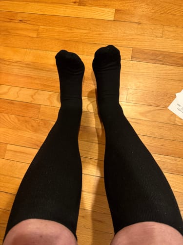 A first-person view of a customer wearing the black Performance Eucalyptus Compression Socks on their legs.