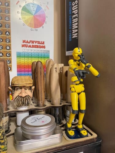 Customer's yellow Solar Flare Stickybones figure in a dynamic pose on a wood carver's workbench.