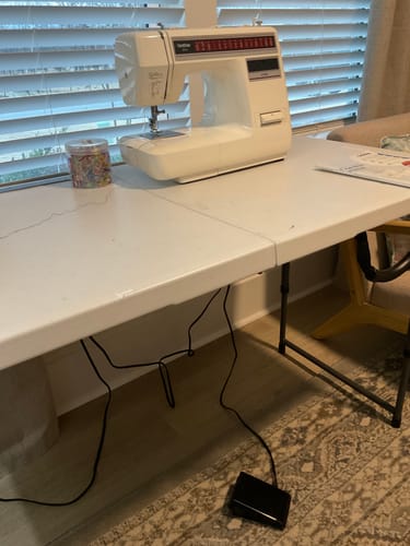 Customer's foot control and cord connected to a Brother sewing machine on a white table, ready for a project.