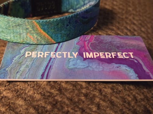 Customer's Perfectly Imperfect Bracelet shown next to its colorful card which reads 'Perfectly Imperfect'.