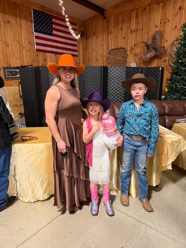 Customer's child wearing the sparkly pink Kids' Glitter Waves Western Boots with a dress and cowboy hat at an event.