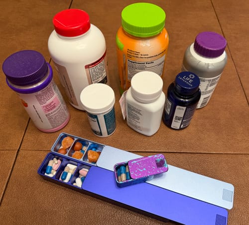 Customer's open Weekly AM-PM Vitamin Case 2.0, organizing pills from several supplement bottles shown in the background.