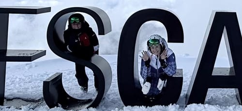 A customer wearing white Gsou Snow Sheepskin Gloves while posing in the snow with a friend.