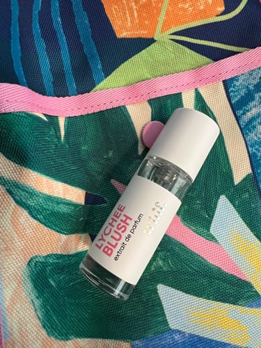 Customer's bottle of Lychee Blush perfume resting on a colorful, patterned bag.