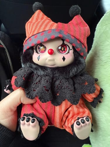 A customer holding their detailed Cino's Dreamland Circus Series plush toy, which has a red and black jester outfit.
