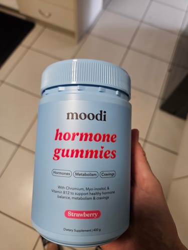 Customer holding a light blue bottle of Moodi Strawberry Hormone Gummies.