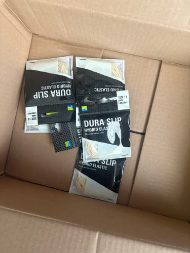 Recensent toont verschillende verpakkingen DURA SLIP HYBRID ELASTIC in een geopende verzenddoos.