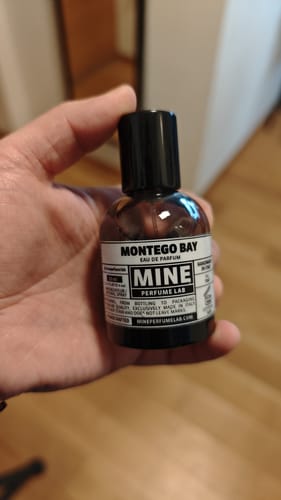 Un recensore tiene in mano la piccola boccetta di profumo Montego Bay.