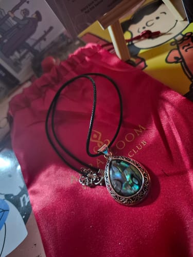 Customer's teardrop abalone shell necklace from the VIP Crystal Club resting on a red bag.