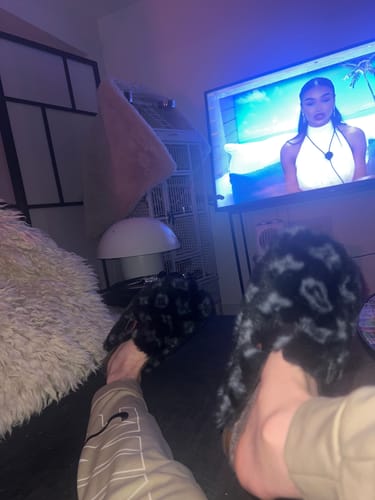 Reviewer relaxing with their feet up, wearing the fuzzy Abstract Spotted Faux Fur Buckle Clogs indoors.