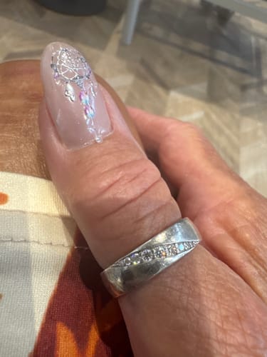 Close-up of a reviewer wearing the wide-band Halsten ring on their thumb, showing off the channel of moissanites.