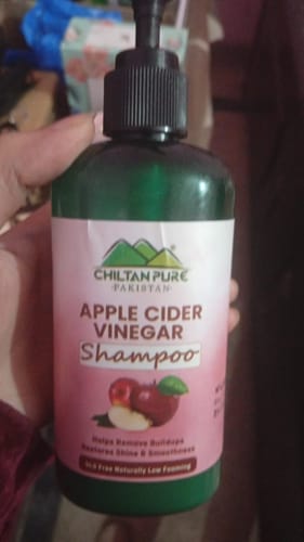 A customer holding the green bottle of Chiltan Pure Apple Cider Vinegar Shampoo.