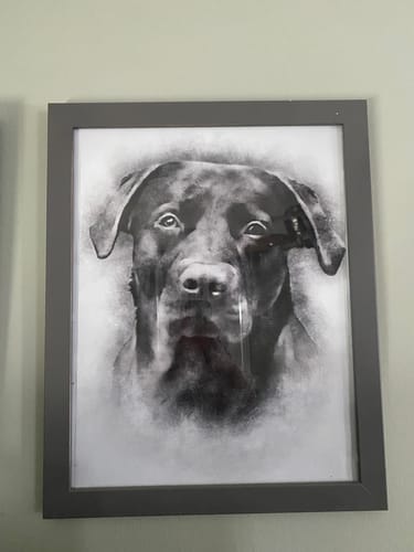 Customer's personalized portrait print of a dog. The black and white sketch is mounted in a dark frame and hung on a wall.