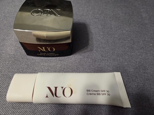 Customer's BB Cream SPF30 tube and Snail Cream jar, both mentioned in the review, on a grey surface.