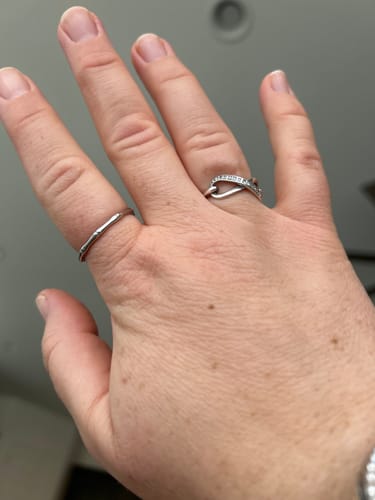 Reviewer's hand wearing two silver-colored rings from the jewelry bundle: a simple band and an infinity-style pavé ring.