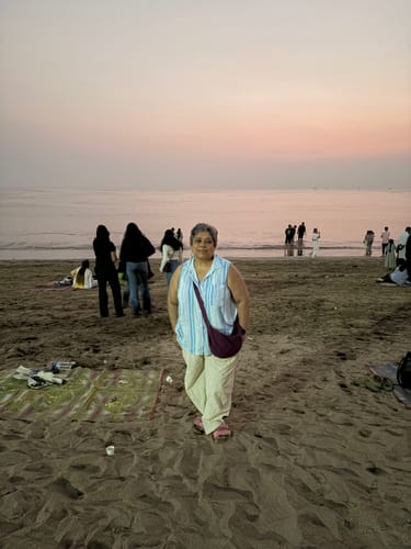 Reviewer standing on a beach at sunset wearing the light-colored Dhoti-Cut Yog Pants.