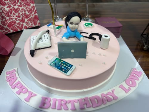 Customer's pink Workaholic Cake with detailed fondant decorations of a person with a laptop and work accessories.