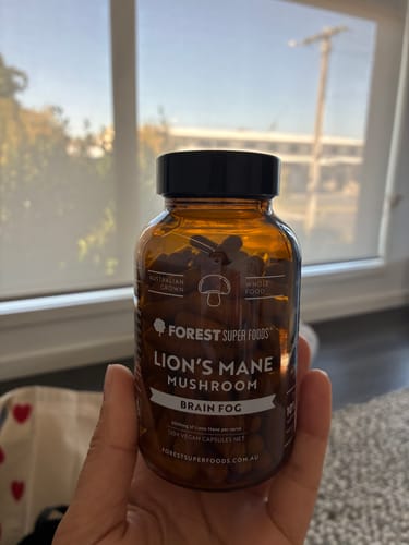 Customer holding a brown bottle of Lion's Mane Mushroom capsules for brain fog.