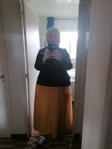 Cliente prenant un selfie dans un miroir portant la longue jupe Sarah en lin ocre.