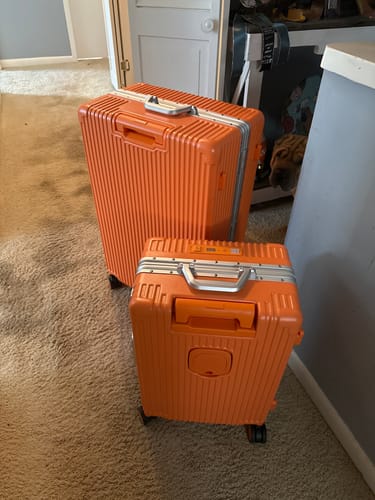 Customer's orange All-in-One Carry-On shown next to a matching full-size suitcase in a room.