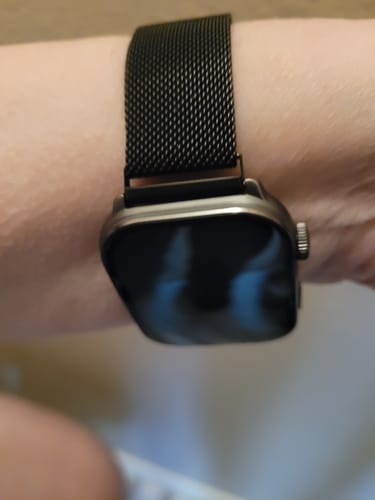 Close-up of a reviewer's wrist wearing the black mesh milanese strap attached to a watch.