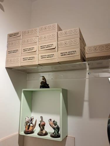 Client montrant plusieurs boîtes de mouchoirs en carton empilées sur une étagère.