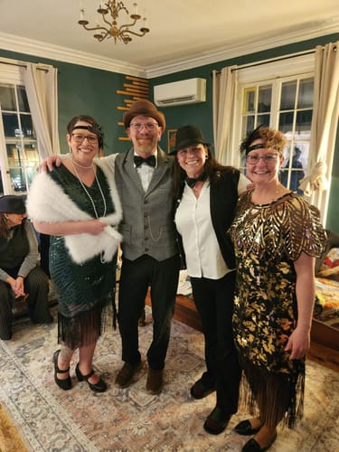Reviewer and three guests in festive 1920s costumes posing while playing the Murder Mystery Game Kit.