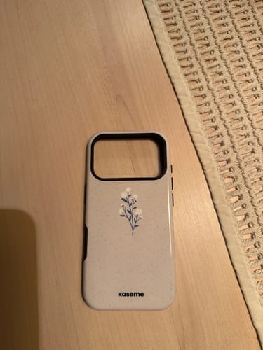 Reviewer's Chloé Beige phone case with a delicate floral design lying on a table.