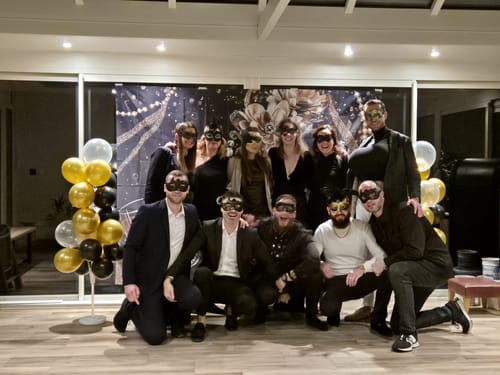 Customers posing in black masquerade masks at a party while playing the Murder Mystery Game Kit.