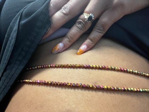 Customer showing two iridescent strands of Sparkle Lux Tie On Waist Beads worn on their waist.