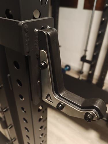 Rezensent zeigt den hochwertigen R7 J-Hook in der Nahaufnahme, der sicher an einem schwarzen Rack befestigt ist.