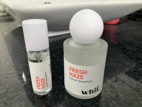 A customer's two bottles of Fresh Haze perfume, one large and one small, on a black countertop.