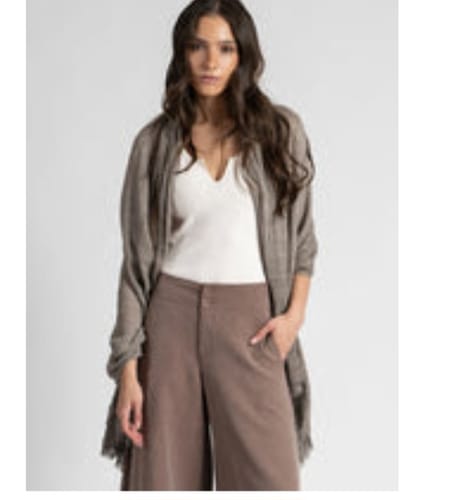 Una clienta muestra el top MAYA acanalado en color crudo, que lleva debajo de un cárdigan abierto.