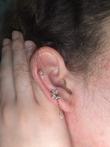 Close-up of a customer's ear, showing the gold Climbing ivy flatback earring worn in a cartilage piercing.