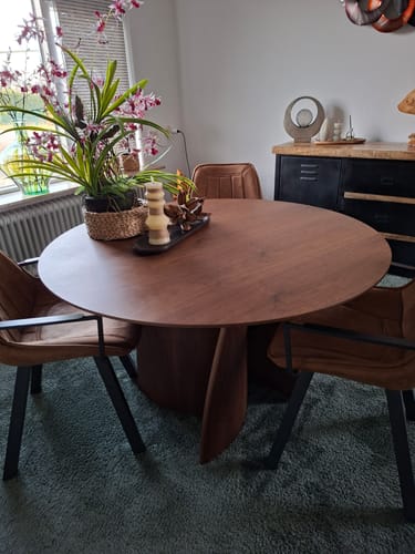 Klantfoto van de ronde by fonQ Swirl eettafel van walnoot, opgesteld in een sfeervolle eetkamer.