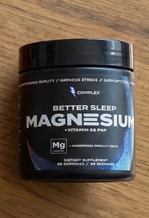 Customer's black jar of Complex Better Sleep Magnesium supplement sitting on a wooden table.
