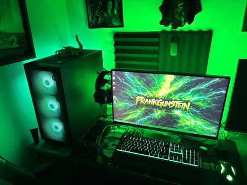 Reviewer's custom iD Colossus mousepad as part of a green-lit gaming setup with a matching wallpaper.