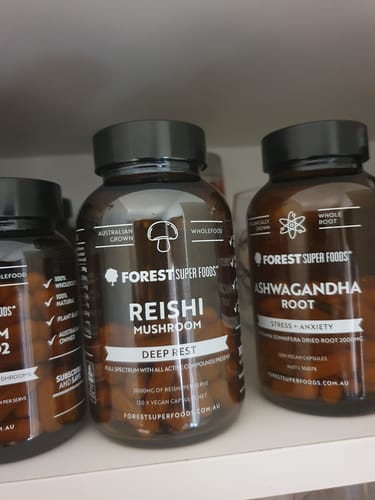 Reviewer's brown bottle of Reishi Mushroom capsules sitting on a white shelf next to other supplement bottles.