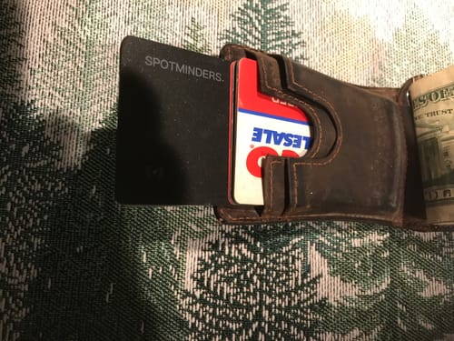 Reviewer's black SPOTMINDERS Tracking Card PRO fitting discreetly into a brown leather wallet.